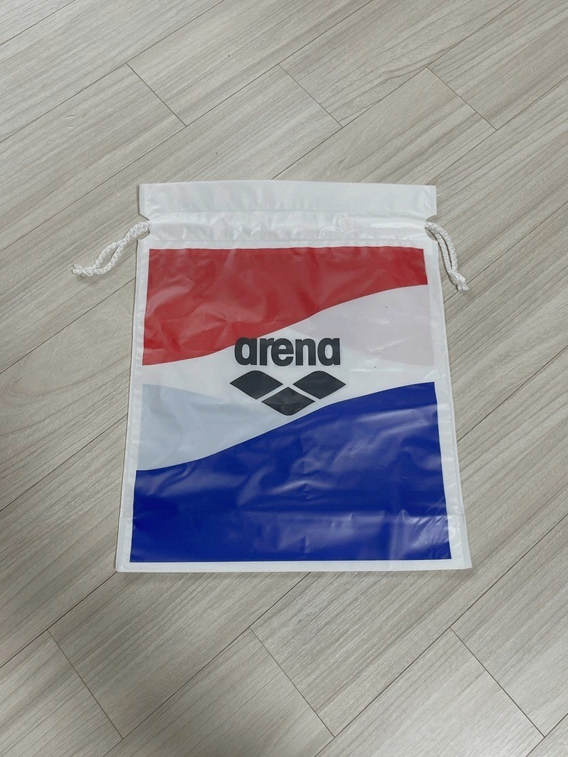 빨강, 흰색, 파랑 바탕에 arena 로고가 있는 흰색 끈 주머니형 가방