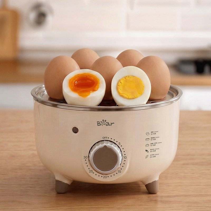 앞면에 다이얼과 로고가 보이는 계란찜기 위에 반숙란이 올라간 정면 모습