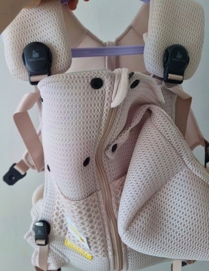 어깨 쪽 검은색 버클과 머리 받침 부분이 보이는 아기띠