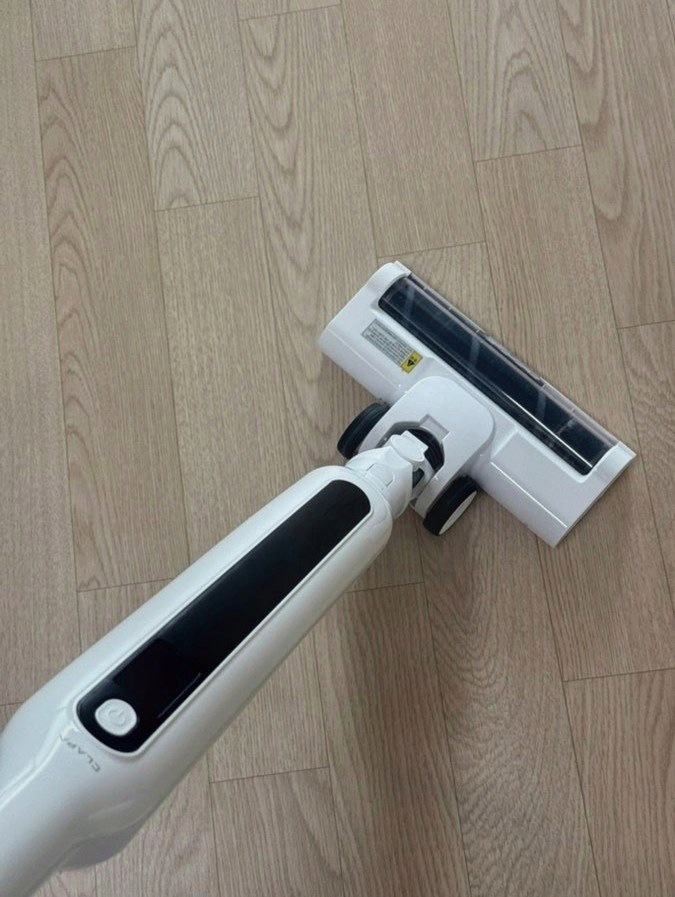 나무 무늬 바닥 위에 놓인 흰색 청소기 헤드