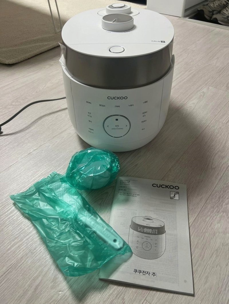 조리대 위 밥솥 앞에 놓인 포장 비닐과 설명서