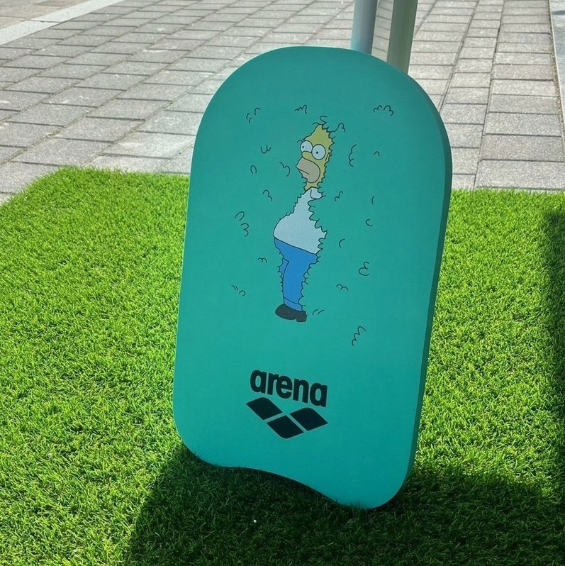 바닥에 세워 둔 민트색 킥판, 캐릭터 그림과 arena 로고가 보입니다