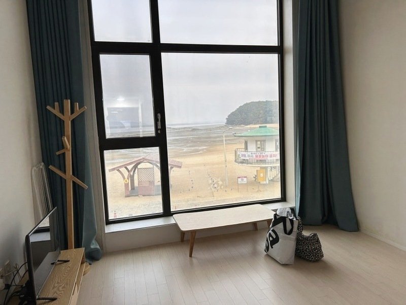 통창 너머로 수기해수욕장 백사장이 보이는 객실 거실