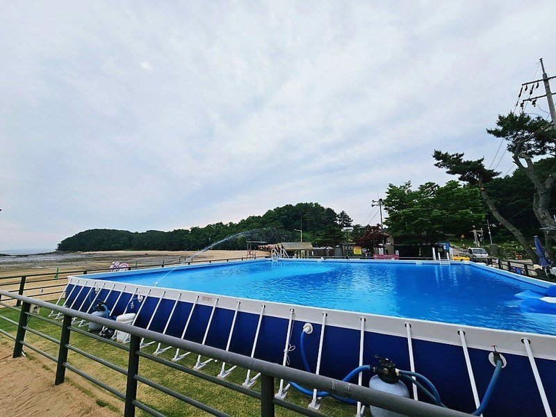 해변 옆 잔디밭에 설치된 대형 조립식 수영장