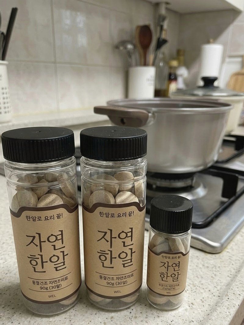 자연한알 병 세 개 뒤로 냄비가 놓인 가스레인지와 주방 조리대