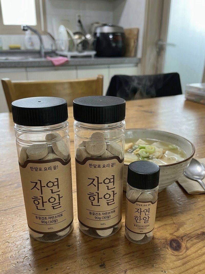식탁 위 국그릇 옆에 놓인 자연한알 큰 병 두 개와 작은 병