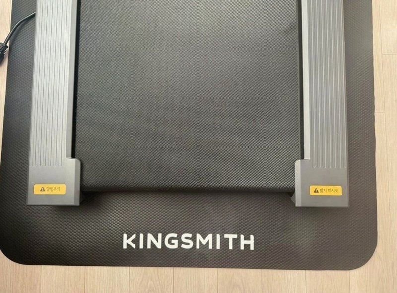 벨트 끝과 KINGSMITH 로고가 보이는 런닝머신 패드