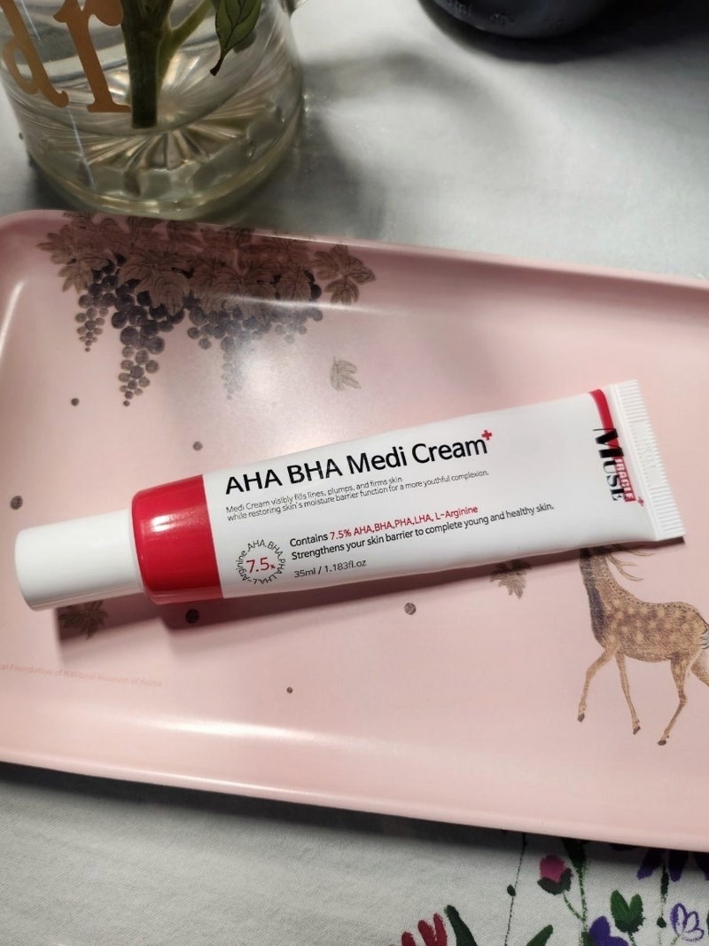 분홍색 쟁반 위에 놓인 AHA BHA Medi Cream 튜브