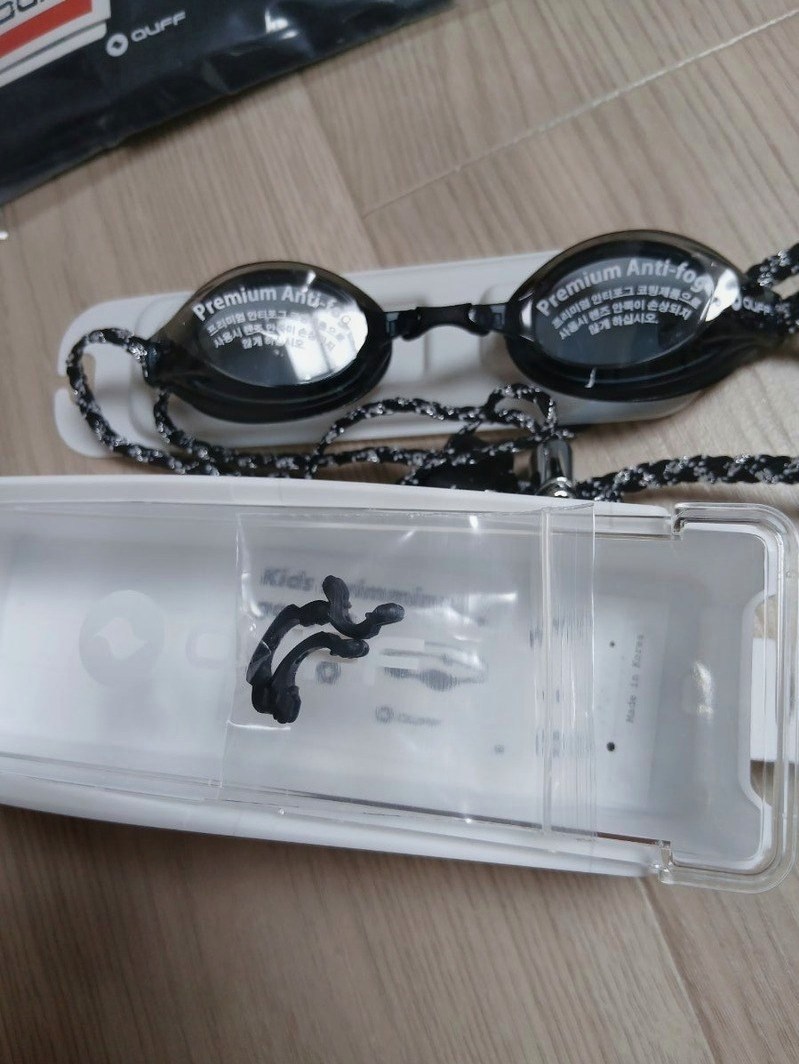 흰색 수경 케이스 안에 들어 있는 수경과 코받침 여러 개