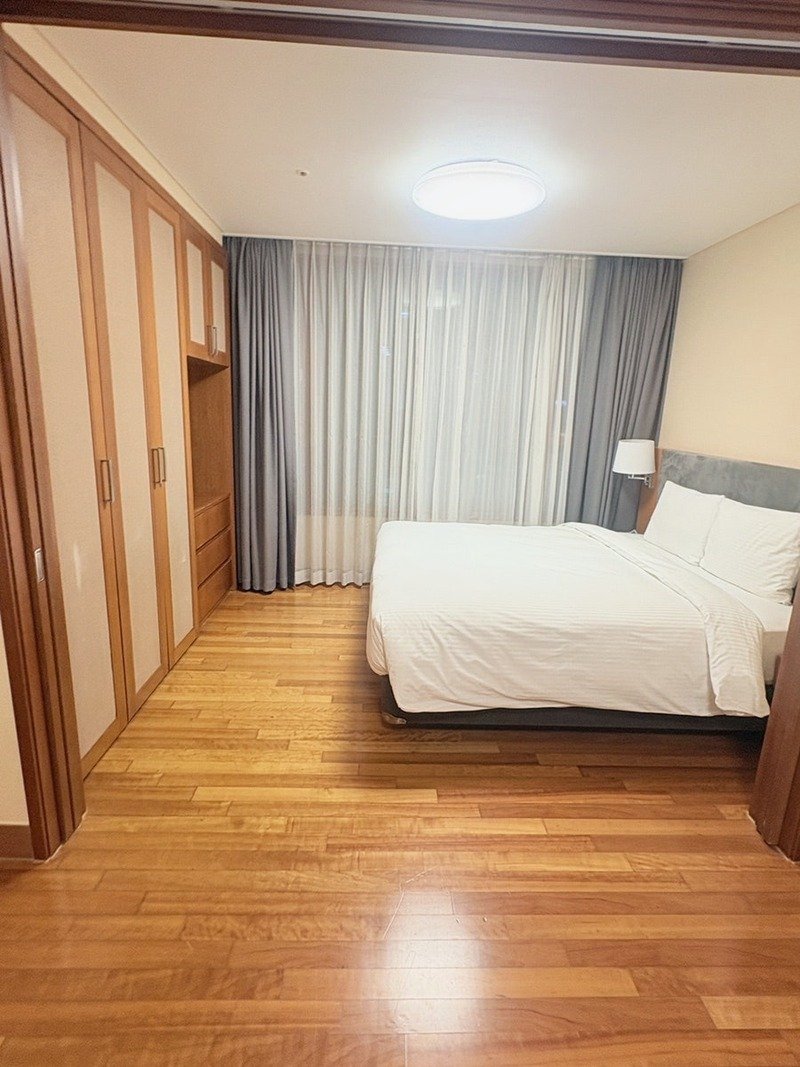창가 쪽 더블 침대와 붙박이장이 있는 침실