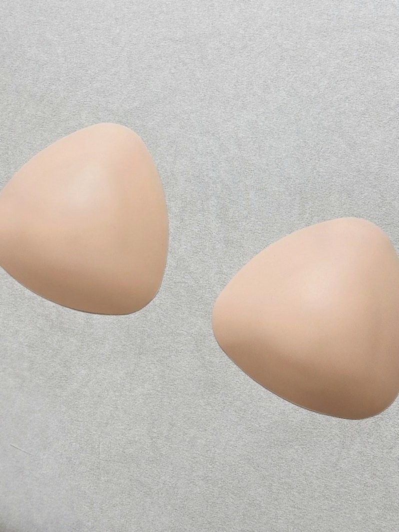 회색 바닥 위에 놓인 살구빛 삼각 실리콘 브라캡 두 개
